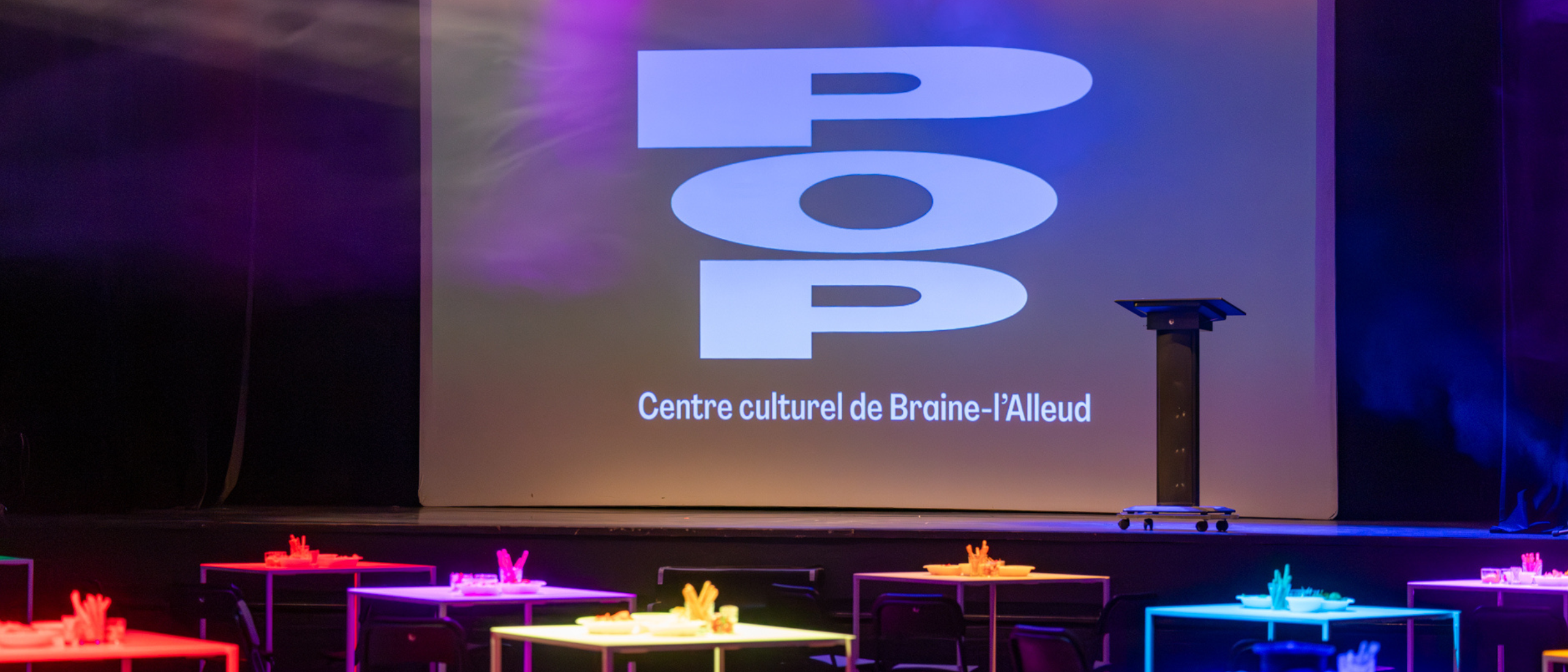Le POP et la salle avant la soirée d'inauguration, scène, écran avec le logo, tables colorées et chouettes lumières