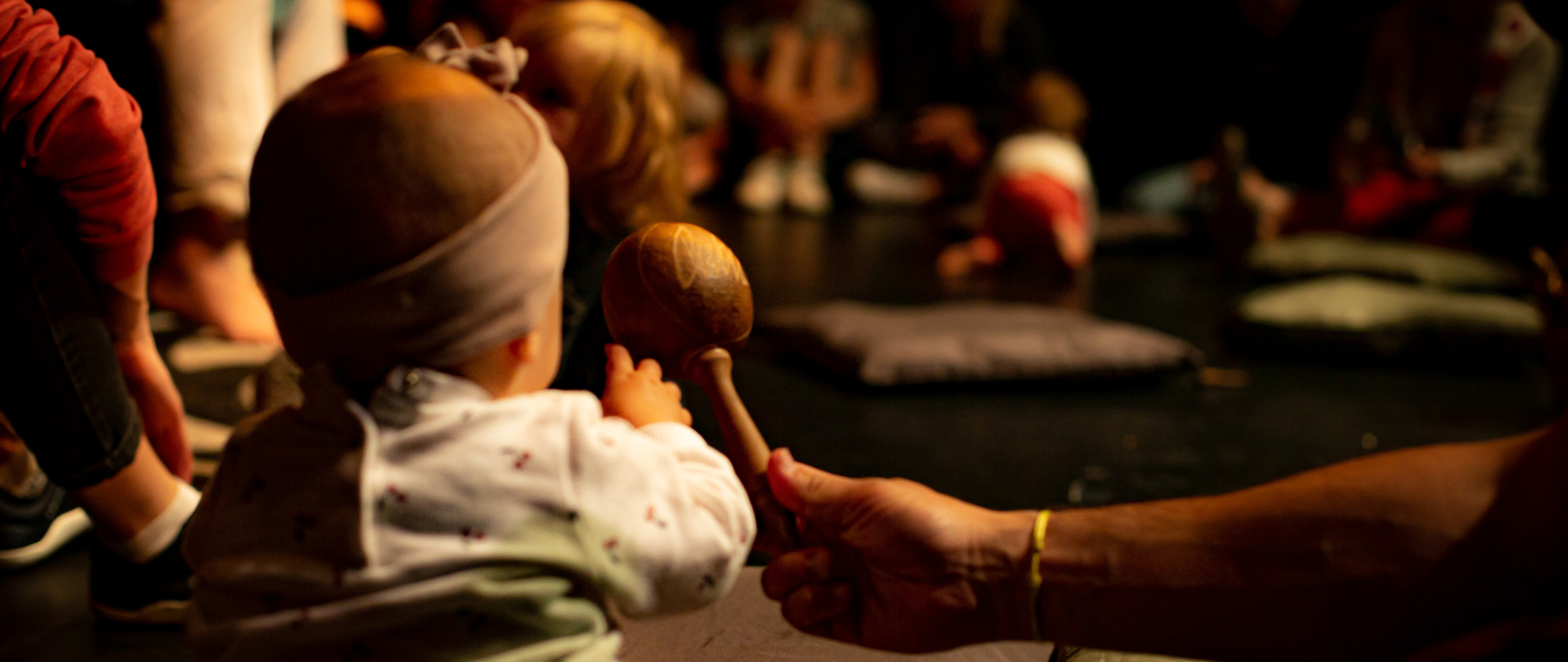 un bébé, de dos, joue avec des maracas pendant le spectacle