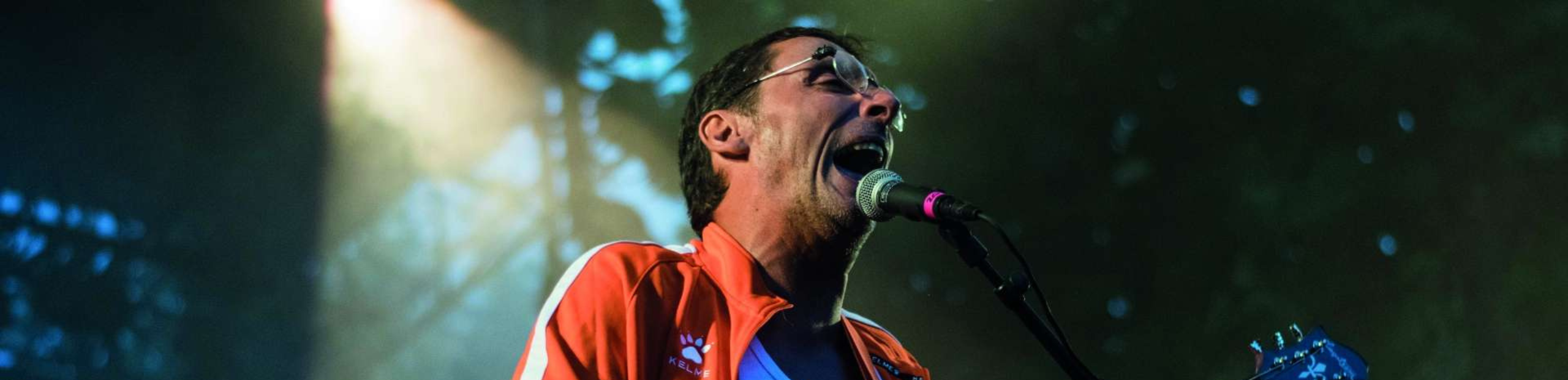 le chanteur Didier super crie dans son micro et joue de la guitare sur scène