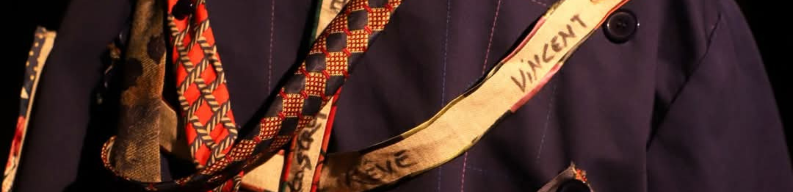 des mains accrochent des bouts de tissus avec des inscriptions sur une veste